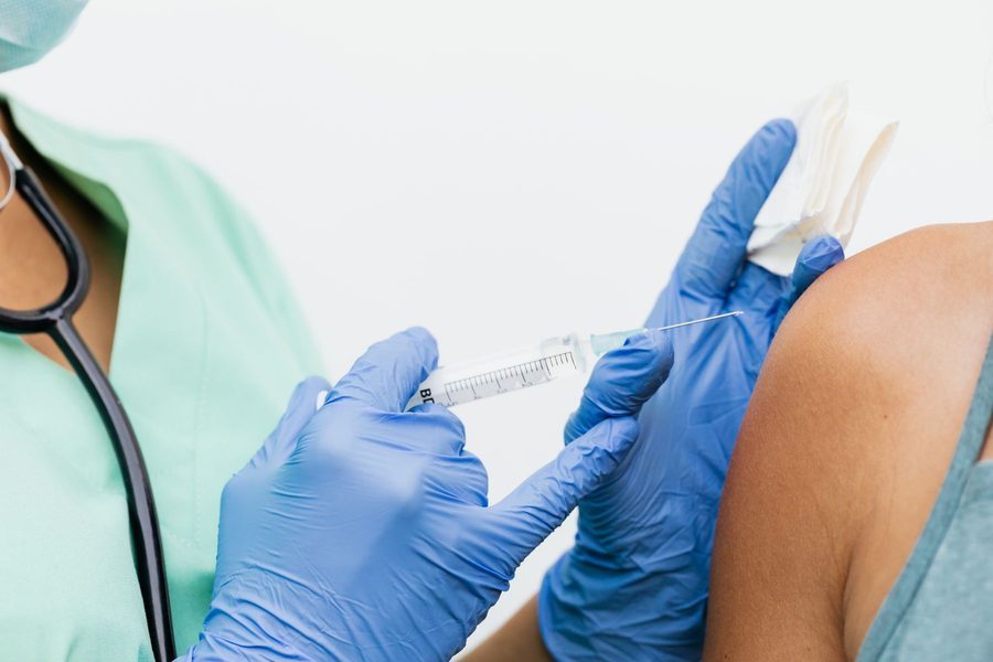 A healthcare professional giving a vaccination in a patient's upper arm